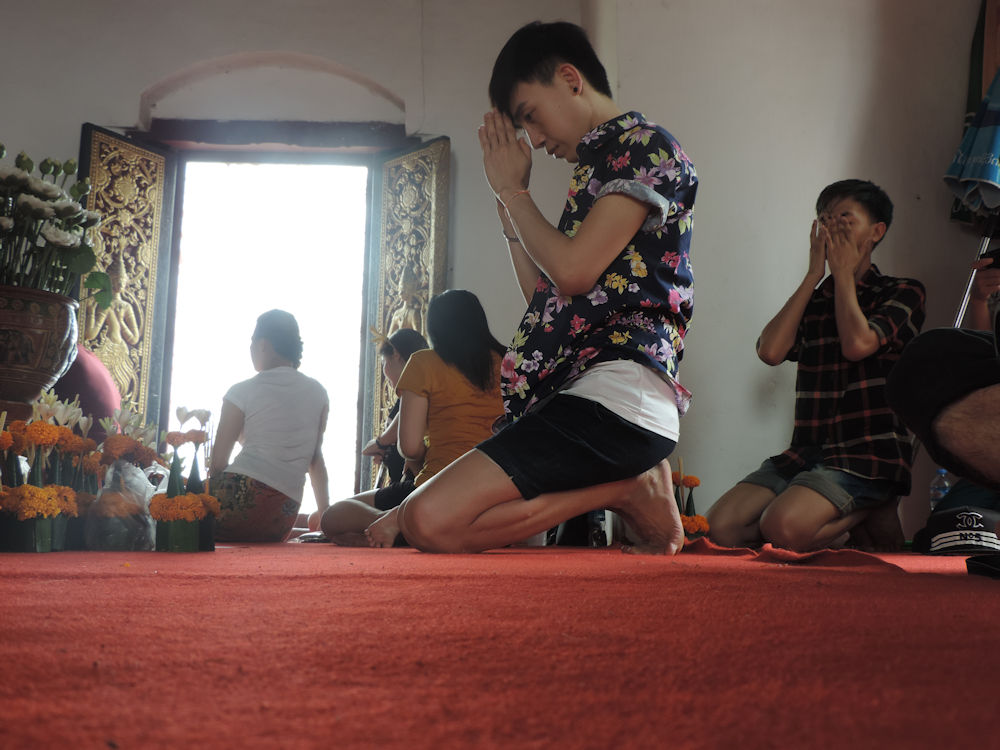 Fieles orando en el templo That Chomsi vecino a la stupa dorada que corona la colina Phu Si, Luang Prabang, Laos